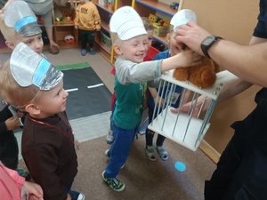 chłopiec wkłada misia- Misiaczka Rozrabiaczka do klatki- więzienia. Obok stoją dzieci