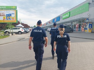 trzech policjantów idących przy centurm handlowym