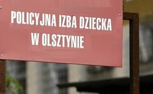 Czerwona tabliczka z napisem Policyjna Izba Dziecka w Olsztynie