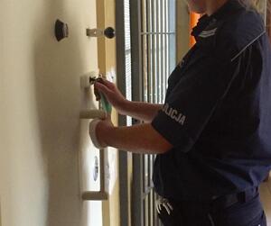 policjant zamykający drzwi pomieszczenia dla osób zatrzymanych