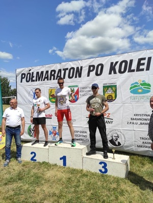 trzech mężczyzn stojących na podium. Na trzecim stopniu podium stoi st.post. Paweł Łukaszuk