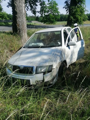 stojące w rowie białe auto osobowe z uszkodzonym przodem