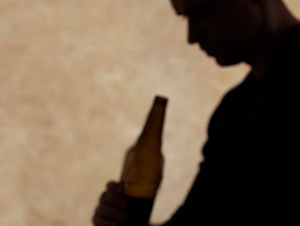 cień człowieka z butelką alkoholu