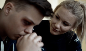 młody mężczyzna z podbitym okiem, pochylająca się nad nim policjantka