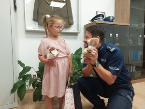 Komendant Powiatowy Policji w Mrągowie w gabinecie wręcza dziewczynce misia