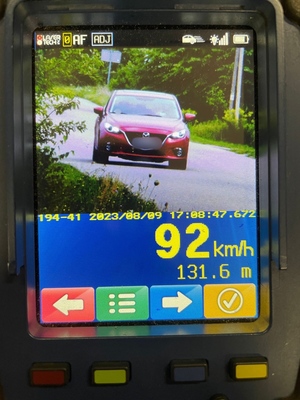 zdjęcie z policyjnego miernika prędkości na którym widać jadący samochód koloru czerwonego i pomiar 92 km/h