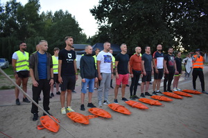 uczestnicy maratonu Hardman stojący na plaży, przed nimi leżą boje pływackie