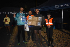 z lewej strony stoi Rafał Syczew, obok niego organizatorzy maratonu, komendant Powiatowy Policji w Ostródzie trzyma karton z prezentem dla zwycięscy