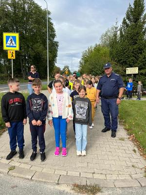 dzieci i policjant stojący przy przejściu dla pieszych