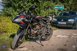 stojący na drodze motorower w tle samochód osobowy