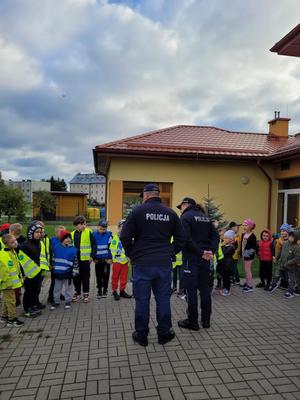 policjanci rozmawiają z przedszkolakami przed budynkiem przedszkola