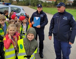 z przodu stoją dzieci z prawej strony strony stoi dwóch policjantów, jeden z nich trzyma w rękach laurkę