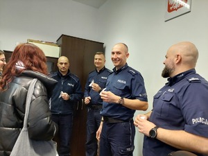 Czterech policjantów w gabinecie przyjmują od kobiet białe wstążki