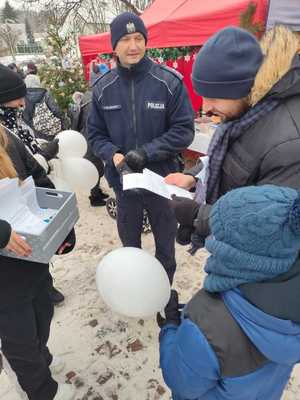 Na zewnątrz stoi policjant a przy nim inne osoby