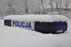 obsypany śniegiem dach radiowozu policyjnego i sygnały świetlno dźwiękowe