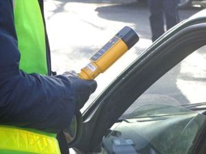 policjant trzymający w ręku urządzenie do sprawdzania obecności alkoholu w ogranizmie