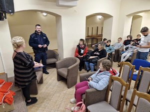 w sali policjant rozmawia z siedzącymi na krzesłach wolontariuszami