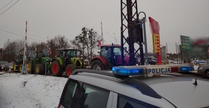 dach radiowozu policyjnego a w tle przejeżdżające ciągniki