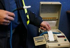 policjant trzymający w ręku element alkometru. Z urządzenia wychodzi wydruk