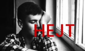 czarno białe zdjęcie chłopca siedzącego przy oknie i napis koloru czerwonego "hejt"