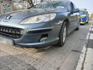 samochód osobowy marki peugeot a za nim radiowóz