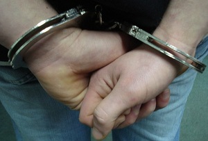 ręce trzymane z tyłu z kajdankami założonymi