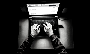 czarno-białe zdjęcie na którym widać piszącą na komputerze postać