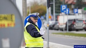 policjant ruchu drogowego dający sygnał ręką do zatrzymania się i ma gwizdek w ustach