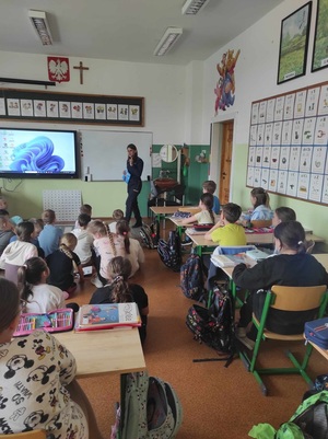 policjantka stoi przed siedzącymi w sali uczniami