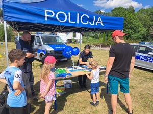 policjantka i uczestnicy pikniku przy stoisku profilaktycznym