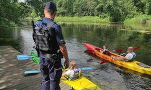 dwa kajaki na rzece i stojący policajnt