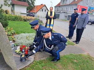 policjanci składają kwiaty i stawiają znicz na obelisku Marka Cekały