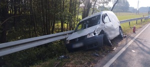 stojący na poboczu rozbity pojazd vokswagen caddy z uszkodzony bokiem i przodem od strony kierowcy