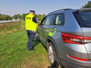 policjant ruchu drogowego rozmawiający z kierowcą pojazdu, który zatrzymał do kontroli drogowej