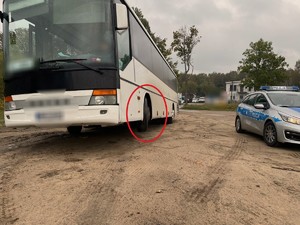 z lewej strony zdjęcia autobus z przednim kołem niedotykającym podłoża, z prawej strony radiowóz