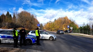 policjanci stoją przy radiowozie i kontrolują ruch drogowy