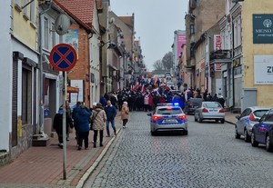 uczestnicy Marszu Niepodległości a w dole ekranu widać jadący radiowóz