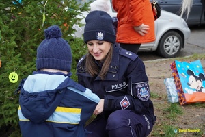 policjantka klęczy przy dziecku i przy choince