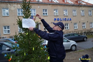 policjant wiesza karteczkę na choince