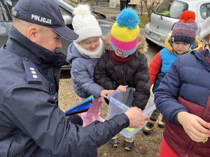 komendant podaje dzieciom odblaski