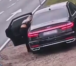 stojący na poboczu samochód i przy nim kobieta