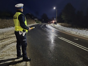 policjant stoi przy drodze z alkomatem