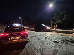 z lewej strony stoi radiowóz a na drodze policjant zatrzymuje pojazd do kontroli trzeźwości