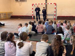 policjant i policjantka stoją na sali przed młodzieżą