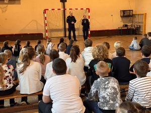 policjant i policjantka stoją na sali przed młodzieżą