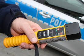 trzymany w ręku alkomat a w tle radiowóz