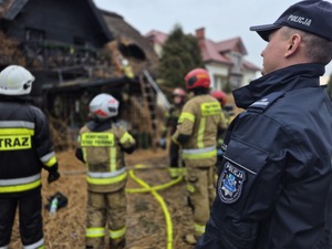 policjant a w tle widać strażaków gaszących pożar