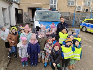 zdjęcie grupowe na którym są dzieci i policjantka a w tle stoi radiowóz
