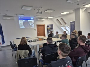 na sali siedzą uczniowie i oglądają wyświetlaną prezentację na której widać policjantów