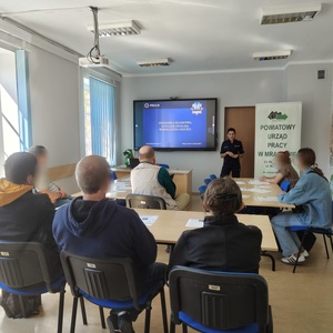 policjantka stojąca na stali za nią wyświetlana jest prezentacja a przed nią siedzą słuchacze